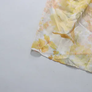 Macro close-up of the delicate yellow floral pattern and hem of a pastoral style dress.