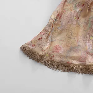 Detail of vintage floral print dress with elegant gold lace fringe hemline finish.