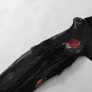 Gros plan d'une manche lanterne noire avec bordure en dentelle et imprimé floral rose rouge.
