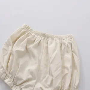 Close-up detail of the ruffled elastic waistband on a solid cream-colored short dress