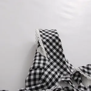 Detalle de un vestido de cuadros blancos y negros con elegante ribete de encaje
