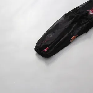 Détail en gros plan d'une manche lanterne en mousseline noire avec dentelle et fleurs