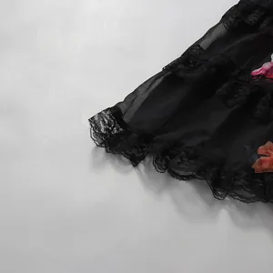 Gros plan sur l'ourlet en dentelle noire et l'imprimé floral d'une robe d'été style français.