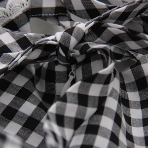 Primer plano de vestido de cuadros blancos y negros con cremallera y lazo decorativo.