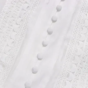 Détail macro de boutons recouverts de tissu blanc et broderie de dentelle sur une robe française