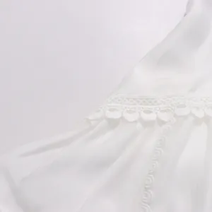 Détail d'une élégante broderie de dentelle blanche sur une robe de style français.