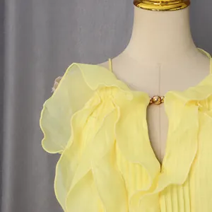 Detail of elegant yellow sleeveless ruffle dress featuring a V-neckline with gold bead accent