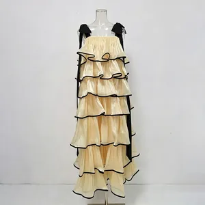 Detailed view of cream tiered ruffle maxi dress featuring elegant black bow shoulder straps
