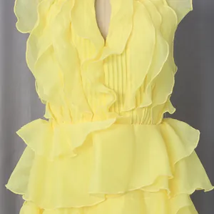 Detailed view of yellow sleeveless dress with tiered ruffles and pleated bodice texture.