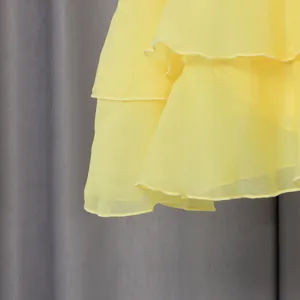 Close-up of yellow ruffled dress hem showing tiered layers and delicate fabric texture.