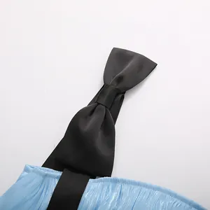 Close-up of black satin bow shoulder strap on a light blue pleated tiered dress
