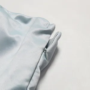 Detailed macro shot of an invisible zipper on a light blue satin formal evening dress.