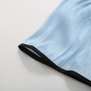 Close-up of light blue textured fabric with black hem on sleeveless maxi dress