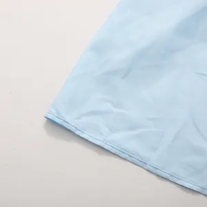 Close-up detail of light blue dress hem showing neat stitching and premium fabric texture.