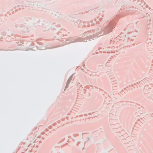 Macro view showing the intricate heavy embroidery and hollowed-out lace of the pink dress