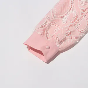 Detail shot showing the pink hollow lace embroidery on a dress sleeve with a button cuff