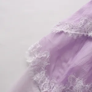 Close-up of white eyelash lace trim on a lavender purple layered tiered dress fabric.