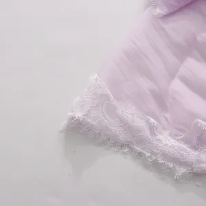 Detail shot of exquisite white eyelash lace trim on a light purple chiffon dress