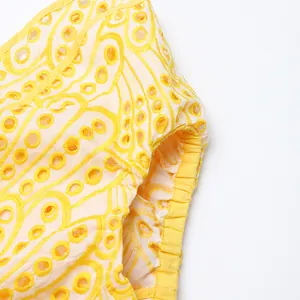 Gros plan sur la broderie anglaise jaune et le détail du poignet élastique d'une robe.