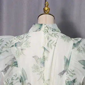 Detailansicht eines französischen Kleides mit Rüschen sowie Vogel- und Blattmuster.