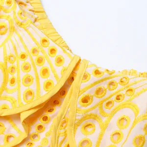Gros plan sur la broderie anglaise jaune complexe et la texture du tissu de robe