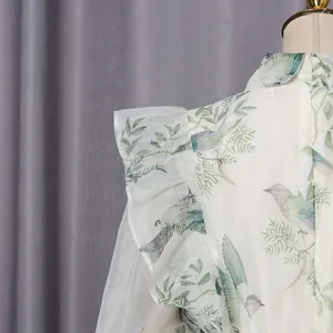 Detailansicht des zarten Vogelmusters und der Rüschen an einem schicken Kleid im französischen Stil