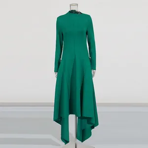 Elegante smaragdgroene jurk met lange mouwen en onregelmatige asymmetrische plooizoom.