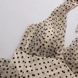 Close-up detail of a vintage halter V-neck dress featuring mesh overlay and polka dots.