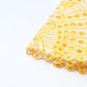 Gros plan sur la dentelle brodée ajourée jaune et blanche avec bord festonné