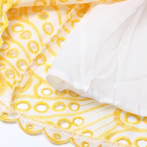 Détail macro de tissu en dentelle brodée jaune avec doublure blanche et bord ondulé