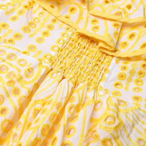 Gros plan sur la broderie anglaise jaune et la taille élastique froncée d'une robe d'été