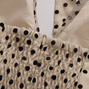 Detailed view of cream polka dot dress with smocked bodice and invisible zipper.