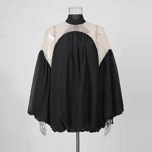 Elegante blusa de gasa negra con paneles de malla transparente y diseño de cuello alto