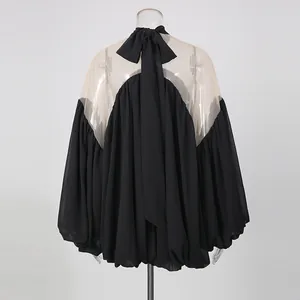 Vista trasera de elegante blusa de gasa negra con malla y detalle de lazo grande.