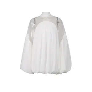 Vista detallada de blusa blanca de gasa con canesú de malla transparente y mangas de farol