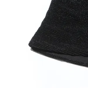 Detailaufnahme des glitzernden schwarzen Plissee-Stoffes für ein elegantes Kleid.