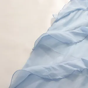 Close-up detail of light blue ruffled chiffon layers with delicate hem stitching on dress