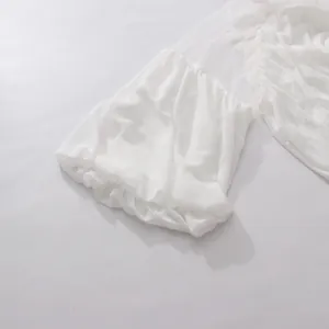 Detalle de la manga abullonada de malla blanca con puño elástico y volantes suaves.