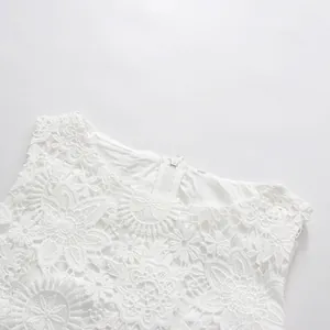 Detail of white sleeveless dress showing intricate lace embroidery and round neckline