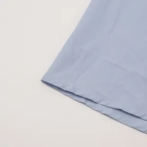 Nahaufnahme des fein genähten Saums eines hellblauen Maxikleides im französischen Stil.