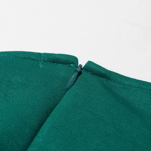 Gedetailleerde macro-weergave van de onzichtbare rits aan de halslijn van een groene jurk