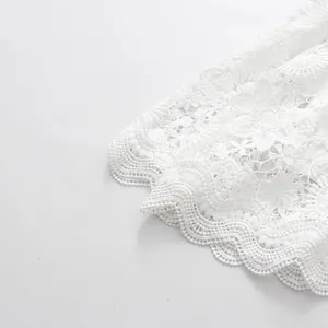 Detailed macro view of high-quality intricate white floral lace embroidery on dress hemline