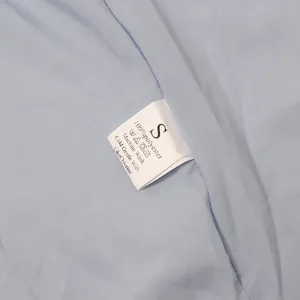 Detailaufnahme des Pflegeetiketts und Größe S an einem hellblauen französischen Abendkleid