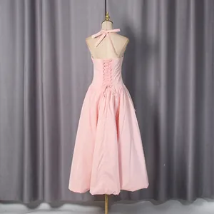 Back view of a pink French halter dress featuring elegant lace-up detailing and a flared skirt.