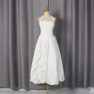 Elegant white halter neck dress with pleated bodice and puffy bubble skirt on mannequin.