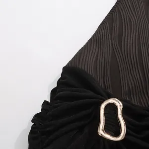 Vue détaillée d'un tissu noir froncé avec boucle en métal doré irrégulière sur la robe.