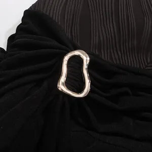 Détail d'une élégante robe noire plissée avec une boucle métallique argentée décorative