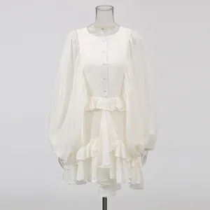 Detailed view of the layered ruffled hem and lantern sleeves on a white court style dress.