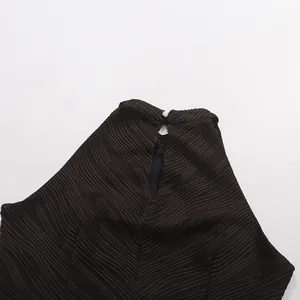 Détail de la texture plissée ondulée et de la fermeture à bouton au dos de cette robe noire.