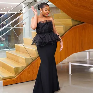 Elegante vestido sirena negro palabra de honor con volantes de malla en una escalera.